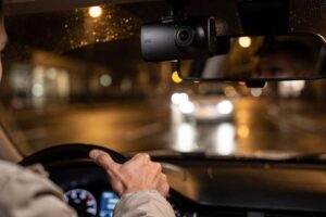 Compact dash camera mounted on vehicle windshield with night vision capability and compact design for budget-conscious UK drivers.