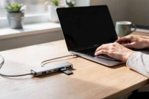 Compact USB-C hub with multiple ports displayed next to MacBook Air for connectivity expansion.