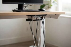 Bundled cables and power cords organized neatly under a standing desk workspace.