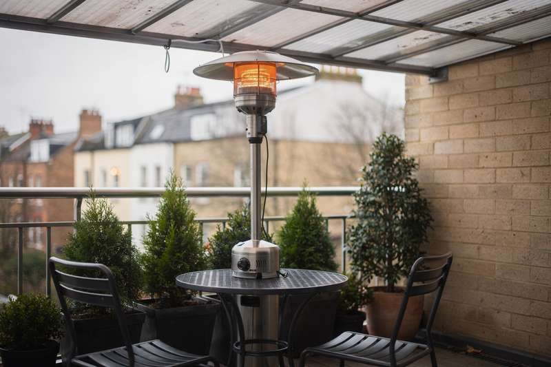 Compact 2kW electric patio heater mounted on a small covered UK balcony, providing efficient warmth for intimate outdoor spaces.