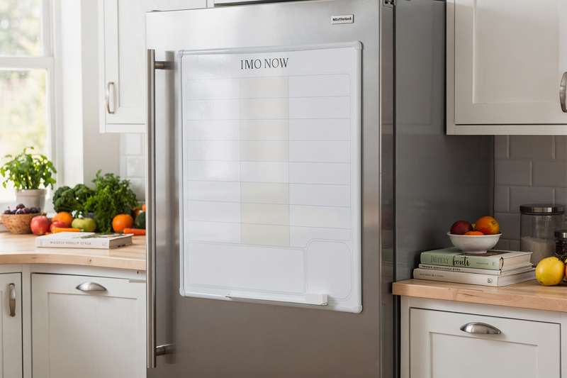 Weekly meal plan template displayed on a magnetic whiteboard attached to a refrigerator.