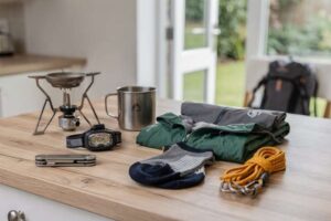 Affordable camping and hiking equipment displayed including tent, backpack, sleeping bag and boots under thirty pounds.