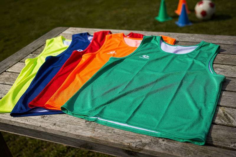 Team sports players wearing high-visibility training vests during group practice sessions.