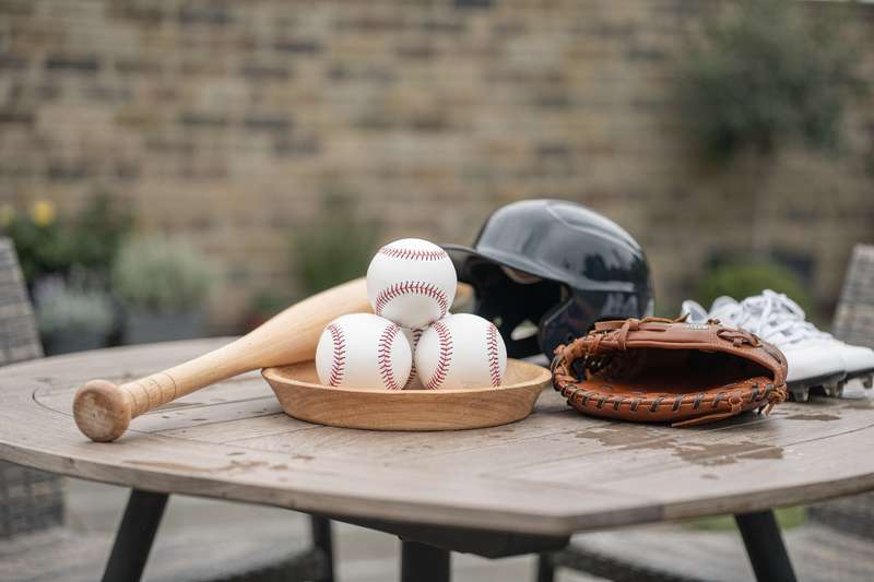 Baseball gloves, bats, and balls arranged on grass for equipment comparison and selection.
