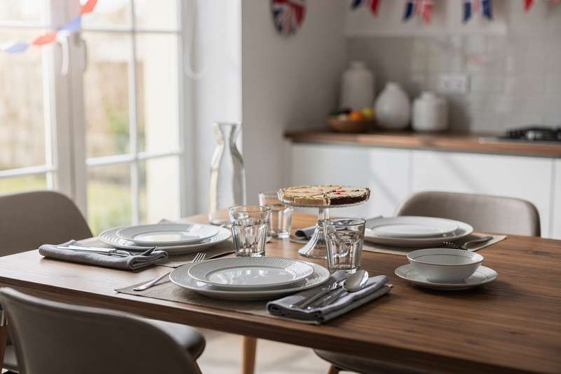 Colorful ceramic plates, glasses, and utensils arranged on a festive table setting for entertaining guests.