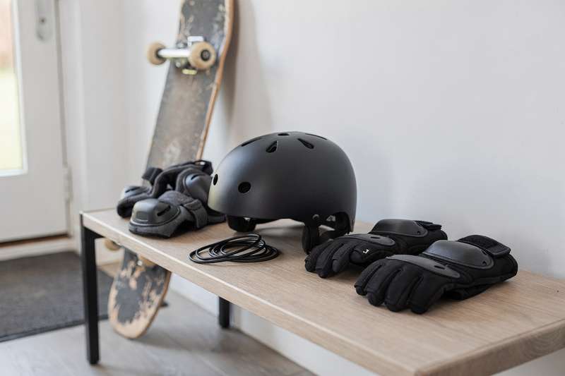 Skateboarder wearing protective helmet, wrist guards, and knee pads during outdoor practice session.