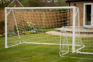 Compact football goal set positioned on a residential UK garden lawn with grass surrounding the frame.