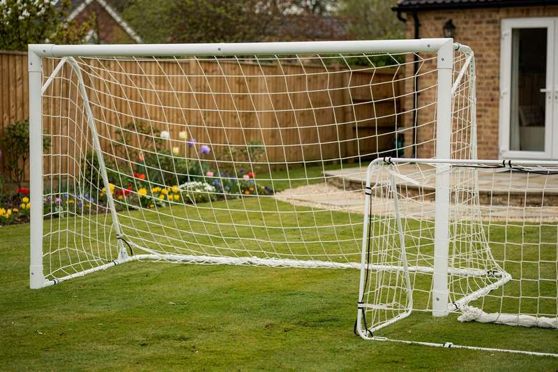 Compact football goal set positioned on a residential UK garden lawn with grass surrounding the frame.
