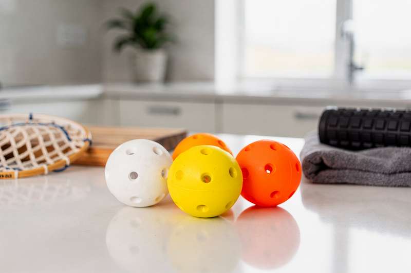 Selection of lacrosse balls in various colors arranged to show sport play, training equipment and massage therapy options.