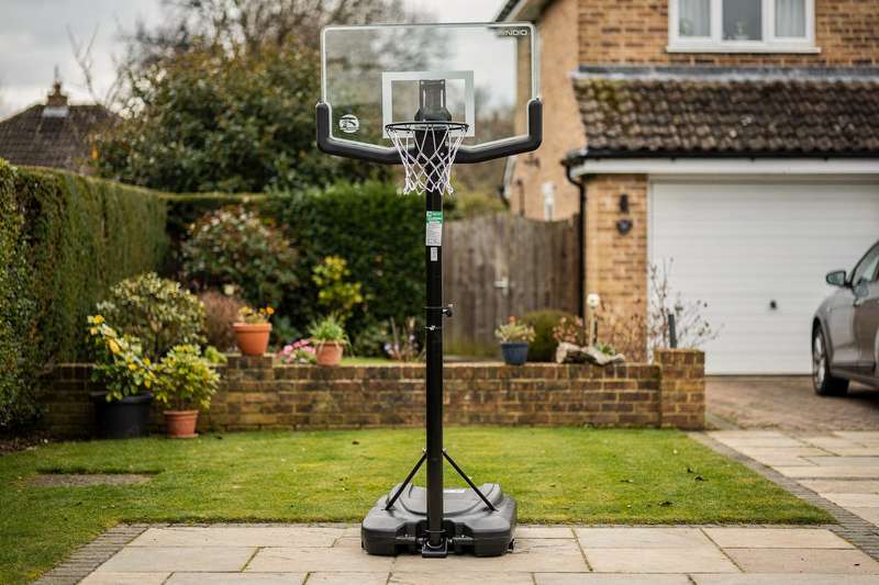 Durable basketball backboard mounted on residential UK driveway with hoop and net.