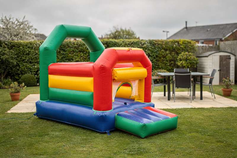 Colorful inflatable bouncy castles set up on a spacious UK garden lawn for children's outdoor entertainment.