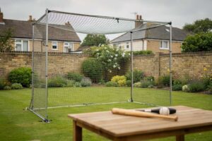 Backyard batting cage setup with netting frame and baseball bat positioned for practice training.